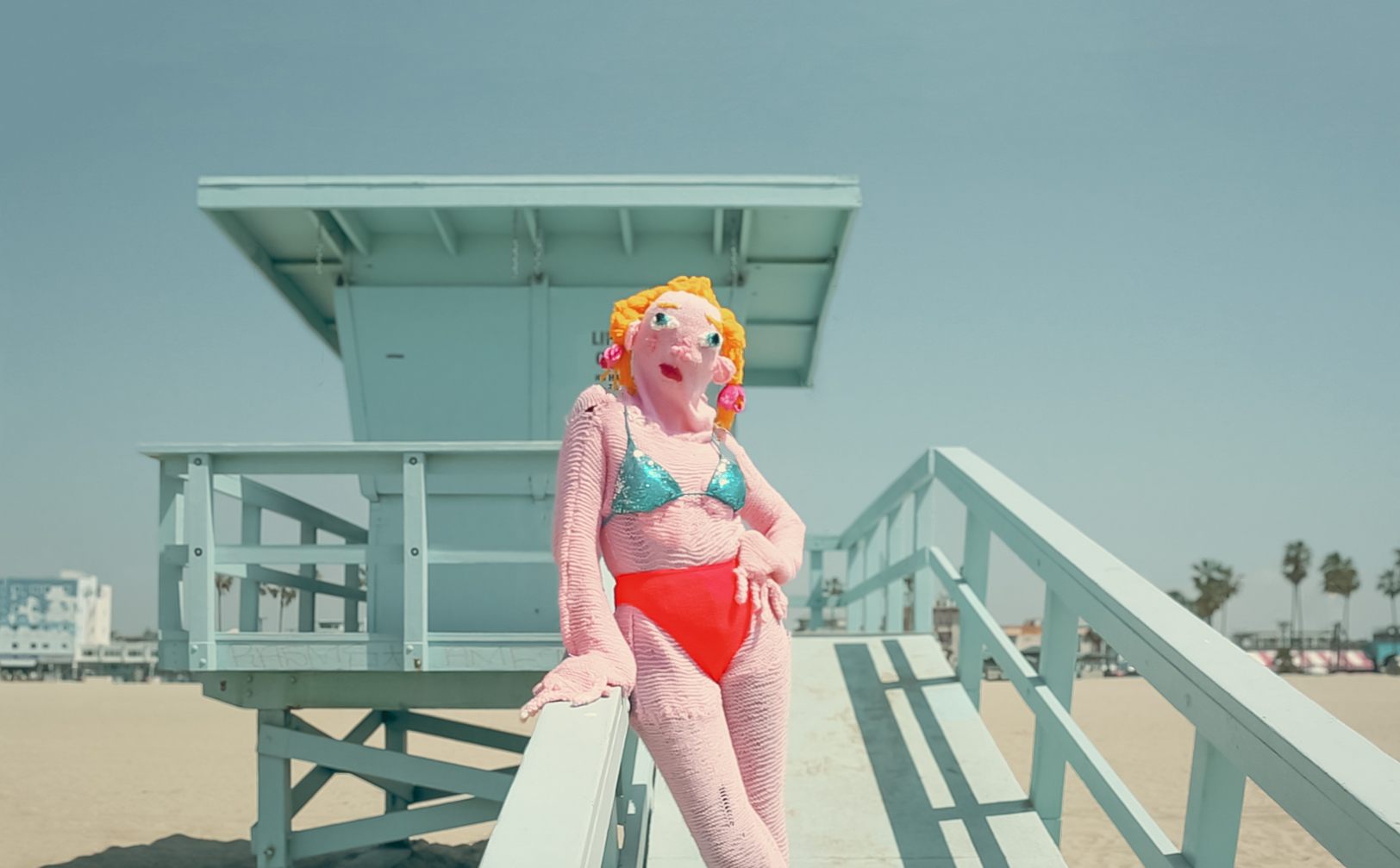 Éva Ostrowska, Venice Beach, pink knitted costume in a sequin bikini at a mint Venice Beach lifeguard tower, photographic performance